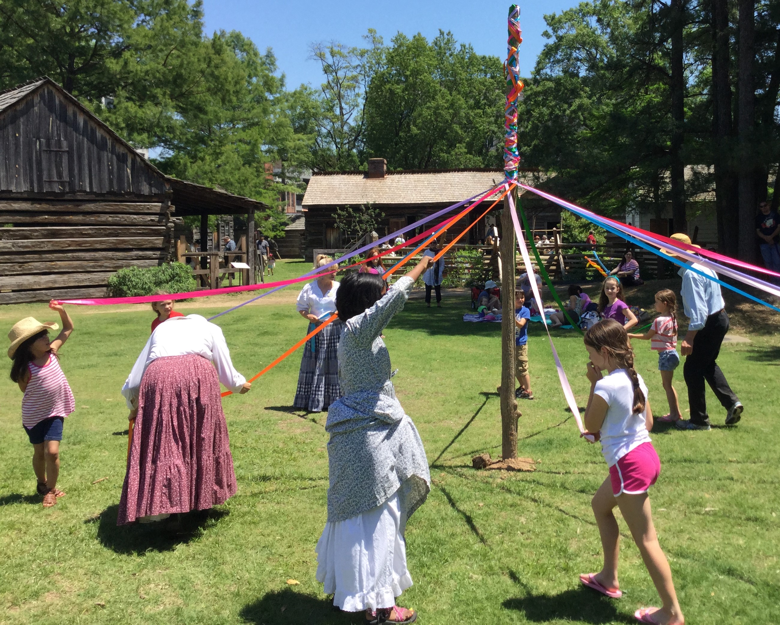 children wrapping colorful ribbons around May Pole